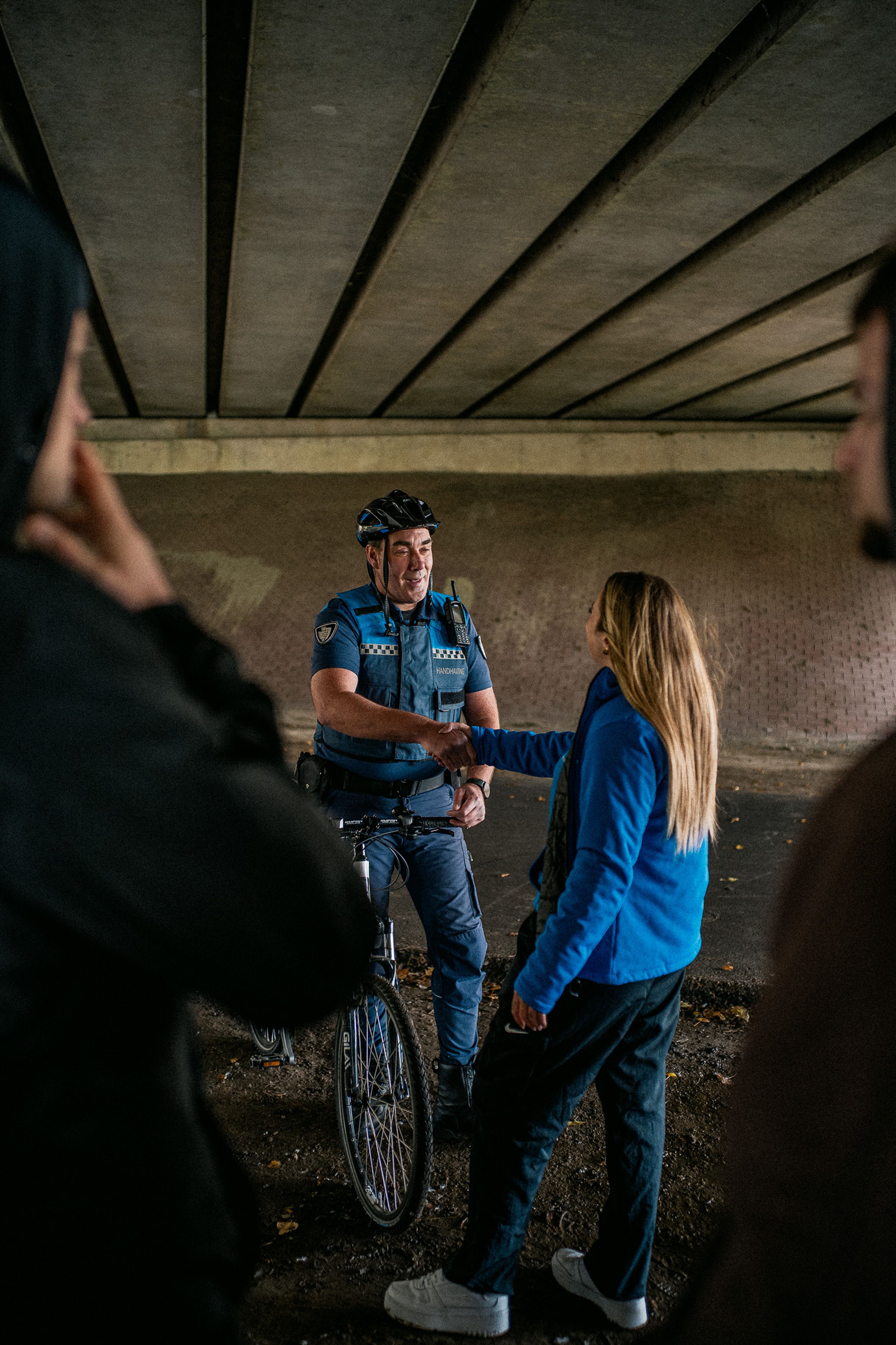 Jongerenwerker geeft Jeugdboa een hand met groepje jongeren in voorgrond