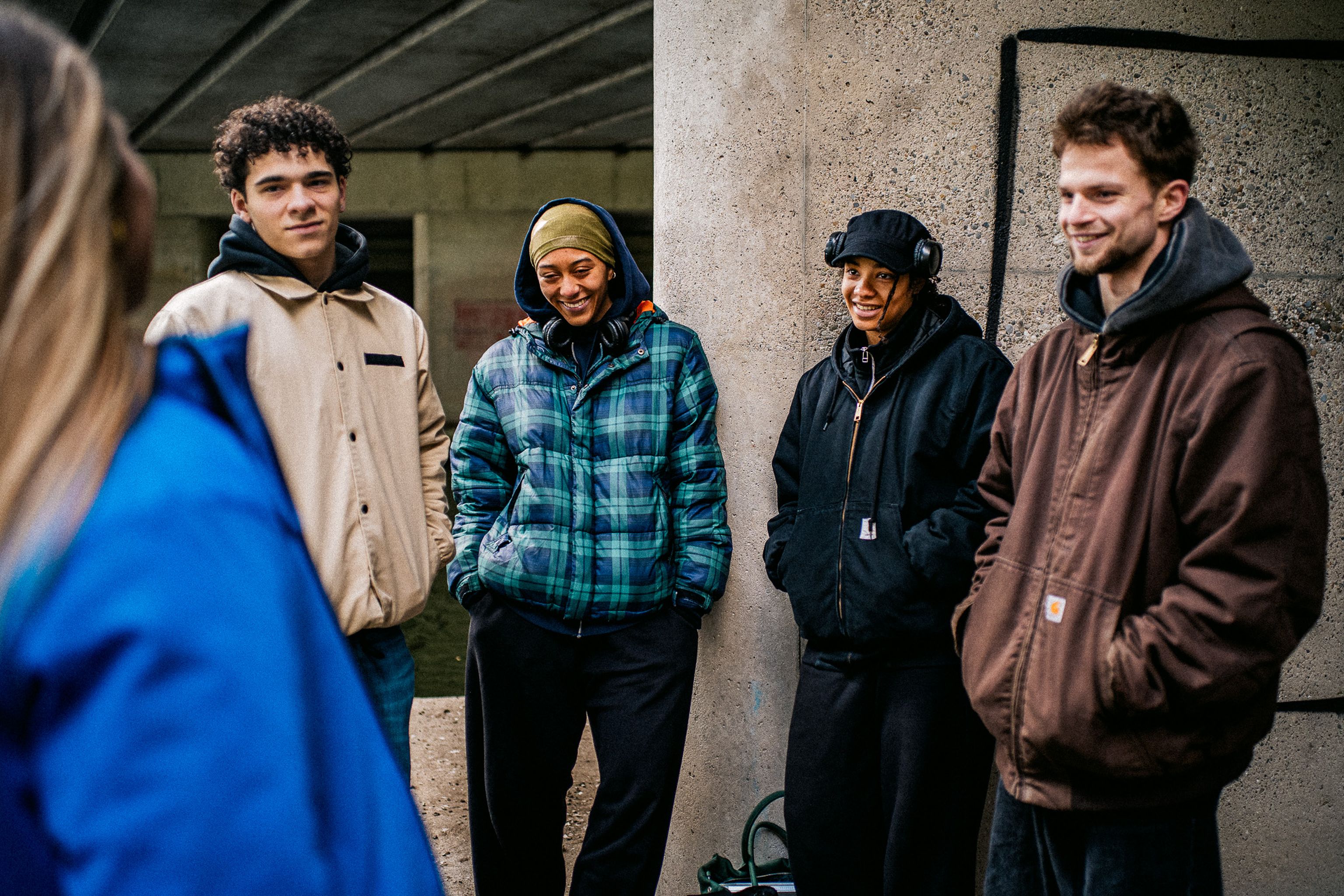 Jeugdgroep in gesprek met jongerenwerker van straatcontact op een hangplek onder een viaduct