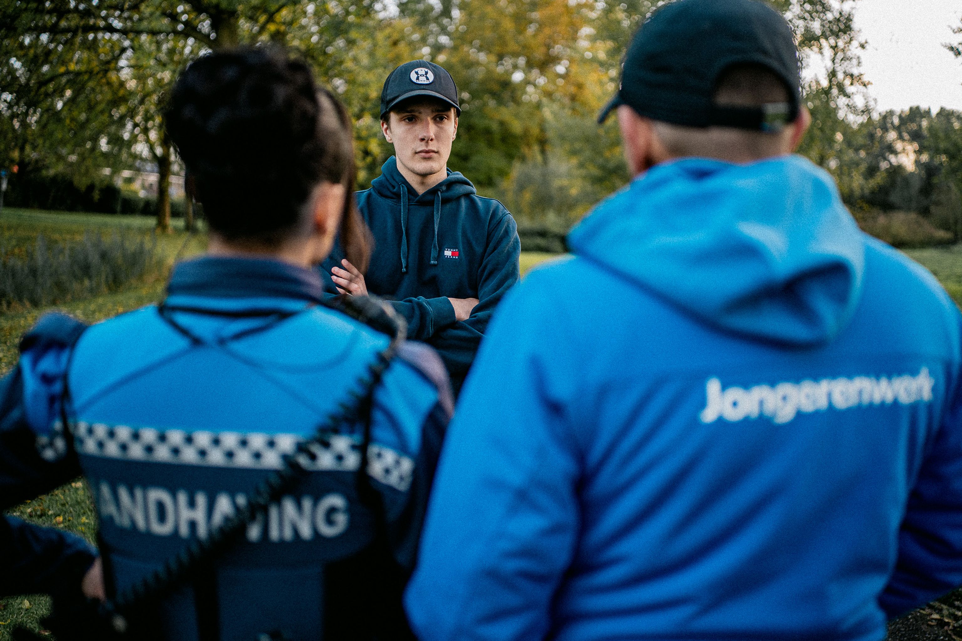 Jongere in gesprek met Jongerenwerker en jeugdboa in een parkje